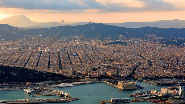 Evening light over Barcelona's city grid and port, with Montserrat on the horizon