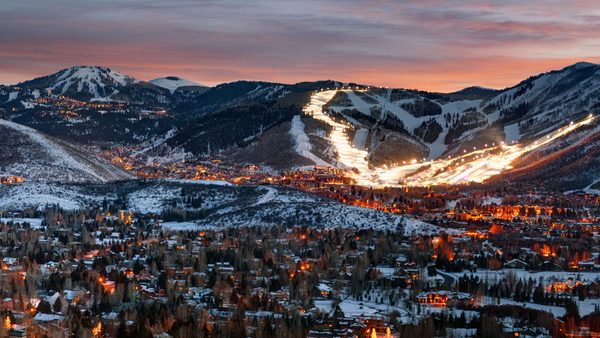 Park City at dusk in winter, with lit ski runs on the mountain above town